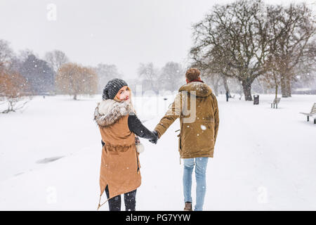 Felice ragazza adolescente passeggiando con il suo fidanzato nel parco sulla neve giorno Foto Stock