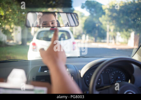 Allievo conducente con istruttore in auto guardando nello specchio Foto Stock