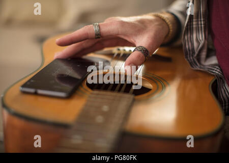 Close-up di mano d'uomo, telefono cellulare e chitarra Foto Stock