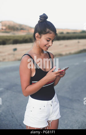 Ragazza adolescente utilizza lo smartphone outddors Foto Stock