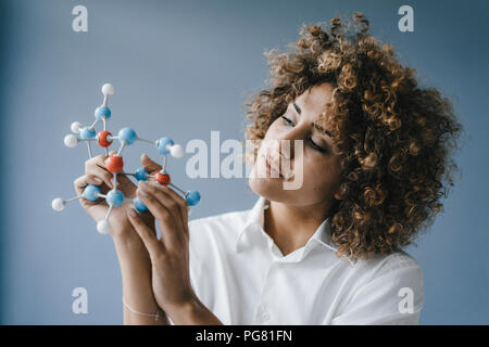 Donna scienziato guardando al modello di molecola, cercando soluzioni Foto Stock