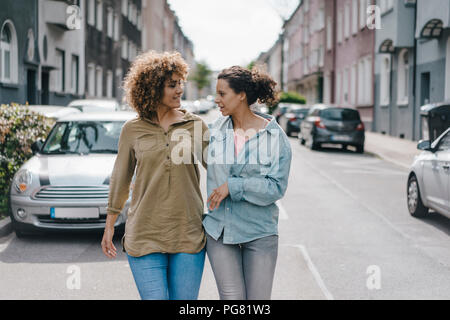 Migliori amici passeggiando nella città, a braccetto Foto Stock