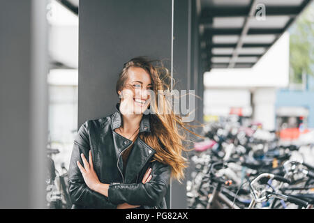 Ritratto di felice giovane donna presso il parcheggio per le bici in stazione in città Foto Stock