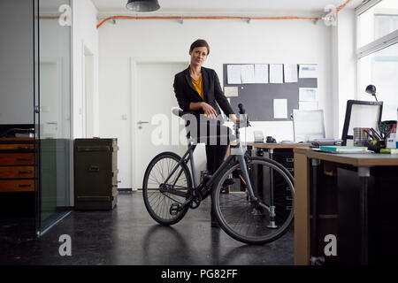 Imprenditrice con bicicletta nella sua azienda start-up Foto Stock