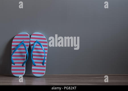 Il rosso e il blu sandalo scarpe sul pavimento di legno contro il muro grigio. Ottimi tempi per ottenere vacanze primavera ed estate concetto. Foto Stock