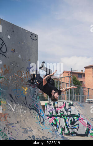 Tatuato uomo che fa parkour in uno skatepark Foto Stock