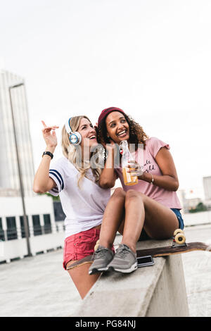 Migliori amici con lo skateboard, divertirsi insieme, ascoltando musica Foto Stock