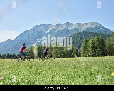 Austria, Tirolo, Mieming, giovane riding bike nel paesaggio alpino Foto Stock