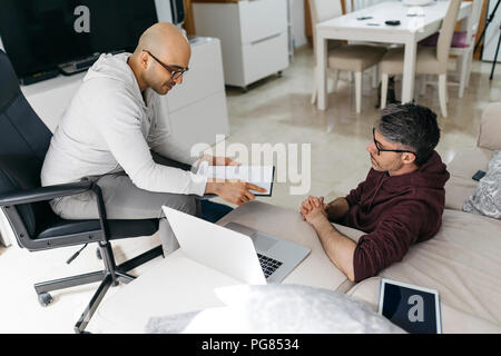 Due colleghi a lavorare su documenti e portatile a casa Foto Stock