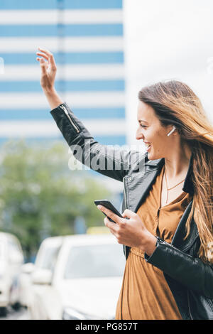 Felice giovane donna con in-ear e telefoni cellulari Foto Stock