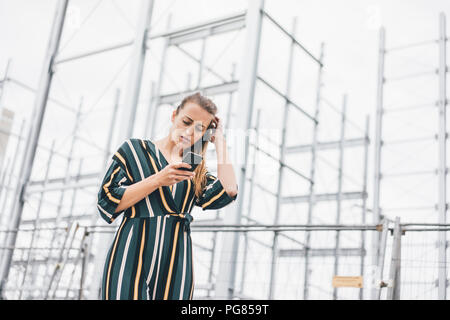 Giovane donna tramite telefono cellulare al ponteggio Foto Stock