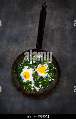 Shakshouka con baby spinat, bietole, cipolline e basilico in padella Foto Stock