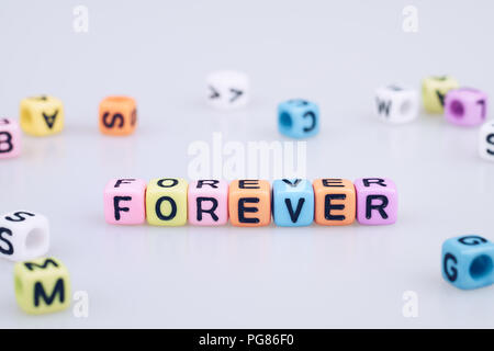 Per sempre parola testo scritto sul cubo colorato con bokeh cube parola sullo sfondo del blocco Foto Stock