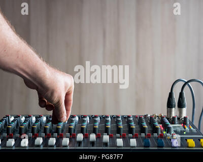 Man mano i pulsanti di regolazione sul mixer audio in music studio Foto Stock