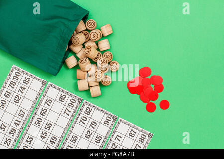 Lotto in legno Barili con borsa di stoffa, gioco di carte e chip rossi su sfondo verde. Gioco di bordo del lotto. Vista da sopra con lo spazio di copia Foto Stock