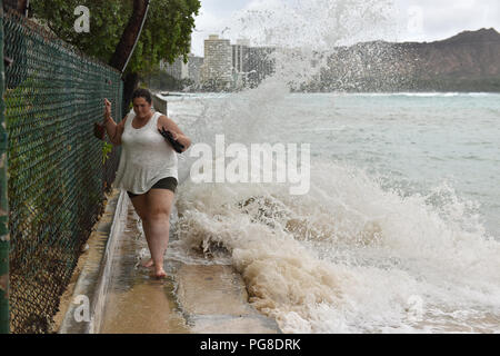 Honolulu, Stati Uniti d'America. 23 Ago, 2018. Una donna cerca di camminare su una strada seashore mentre forti maree lappatura seawall presso la spiaggia di Waikiki a Honolulu delle Hawaii, Stati Uniti, e il agosto 23, 2018. Uragano Lane, predetta come la più grande minaccia meteo alle Hawaii in decenni, spostato pericolosamente vicino alla stato di Aloha giovedì mattina, innescando heavy rain, frane e inondazioni. Credito: Sun Ruibo/Xinhua/Alamy Live News Foto Stock