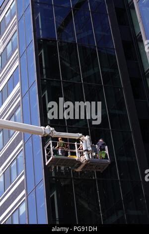 Detergenti per finestre lavorando su di un moderno ed alto edificio di vetro Foto Stock