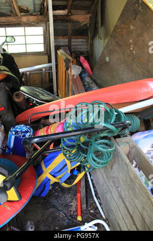 Weathered vecchio capannone per il rimessaggio pieno di elementi di memorizzazione, l'equipaggiamento, estate acqua giocattoli, ammucchiati roba, troppa roba. Foto Stock