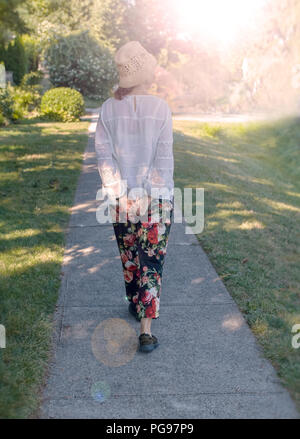 Lady, visto da dietro, passeggiate tranquillamente nel parco. Pomeriggio. Foto Stock