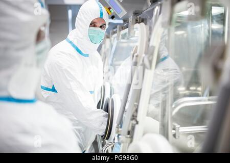 I tecnici al lavoro in sterile sigillato unità isolatore in un laboratorio che produce tessuti umani per l'impianto. Tali tessuti comprendono osso e trapianti di pelle. Foto Stock