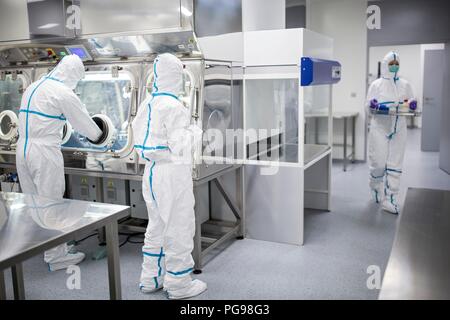 I tecnici al lavoro in sterile sigillato unità isolatore in un laboratorio che produce tessuti umani per l'impianto. Tali tessuti comprendono osso e trapianti di pelle. Foto Stock