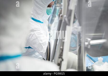 I tecnici al lavoro in sterile sigillato unità isolatore in un laboratorio che produce tessuti umani per l'impianto. Tali tessuti comprendono osso e trapianti di pelle. Foto Stock