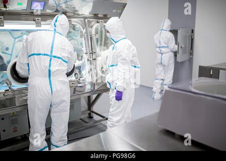 I tecnici al lavoro in sterile sigillato unità isolatore in un laboratorio che produce tessuti umani per l'impianto. Tali tessuti comprendono osso e trapianti di pelle. Foto Stock