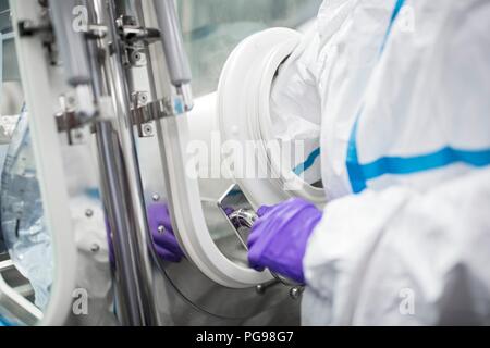 I tecnici al lavoro in sterile sigillato unità isolatore in un laboratorio che produce tessuti umani per l'impianto. Tali tessuti comprendono osso e trapianti di pelle. Foto Stock