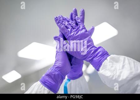 Close-up di tecnici di laboratorio in un ambiente sterile ad alta fiving. Foto Stock