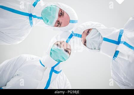 Tecnici di laboratorio indossando tute protettive e maschere facciali in un laboratorio che deve mantenere un ambiente sterile. Foto Stock