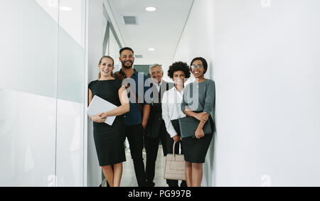 Ritratto di happy business group insieme permanente nel corridoio di office. Multirazziale business professional office in corridoio. Foto Stock