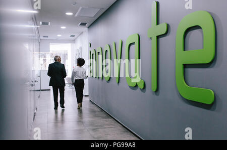 Vista posteriore di due persone di affari a piedi attraverso il corridoio di office. Colleghi di lavoro a piedi in ufficio corridoio. Foto Stock