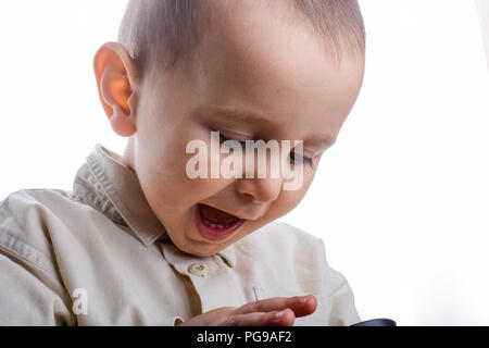 Baby in possesso di una lente di ingrandimento in mano su uno sfondo bianco Foto Stock