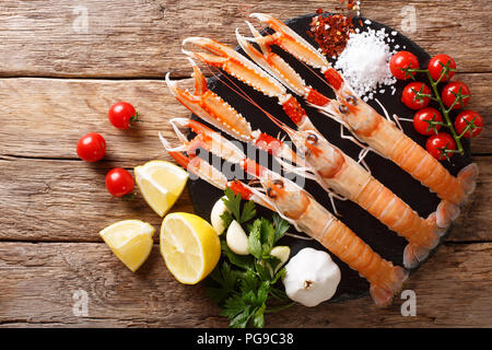Sfondo di cibo crudo fresco langoustine, gli scampi con verdure, erbe aromatiche e spezie close-up su di un tavolo di legno. parte superiore orizzontale vista da sopra Foto Stock