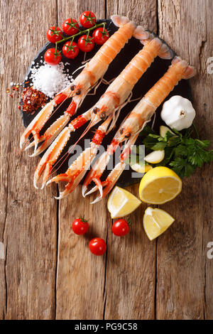 Sfondo di cibo crudo fresco langoustine, gli scampi con verdure, erbe aromatiche e spezie close-up su di un tavolo di legno. Verticale in alto vista da sopra Foto Stock