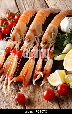 Frutti di mare crudi: scampi o langoustine con verdure, erbe aromatiche e spezie da vicino sul tavolo. In verticale Foto Stock
