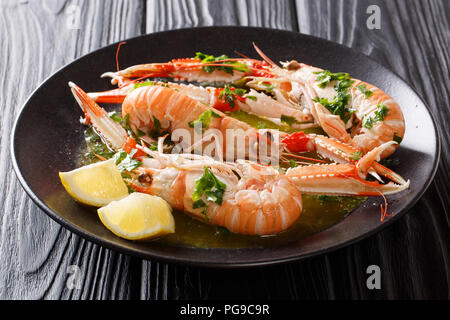 Cucinati Freschi Scampi, scampi con limone e gustosa salsa alle erbe close-up su una piastra su una tavola nera orizzontale. Foto Stock