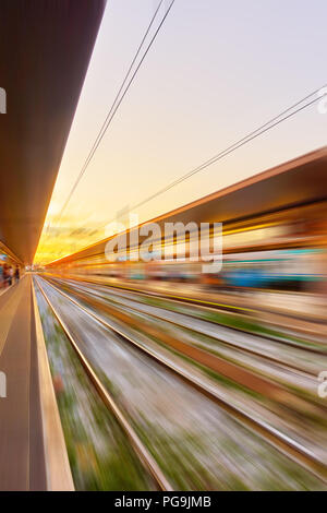 Prospettiva di piattaforme della stazione ferroviaria al tramonto in motion blur - sfondo astratto Foto Stock