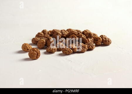 Isolato Tigernuts / massa mandorle / nutsedges su strutturato leggermente la superficie bianca Foto Stock