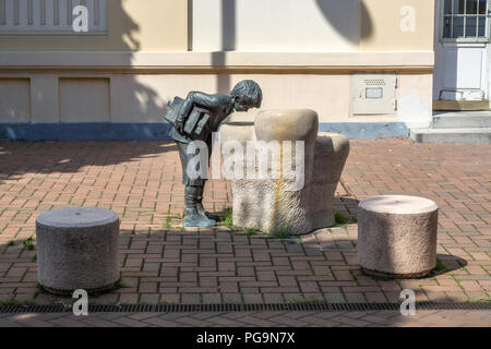 La scultura di un ragazzo che guarda nel pozzo di conoscenze, situato vicino ad una delle scuole di Szeged in Ungheria. Foto Stock