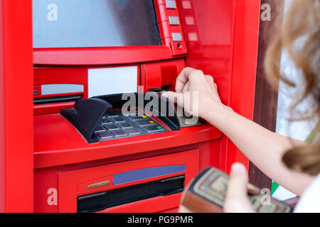 La donna utilizza una carta di credito al bancomat vicino. Funzionamento con denaro Foto Stock