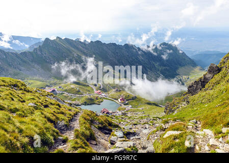 Lago Balea con nuvole sopra dalla vista dall'alto. Luminoso cielo blu su sfondo. Rocce come linee principali. Monti Fagaras, Romania Foto Stock