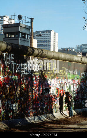 Un Occidente bambino tedesco tenta di chip off un pezzo del muro di Berlino come un souvenir. Una porzione della parete è già stata demolita a Potsdamer Platz. Foto Stock