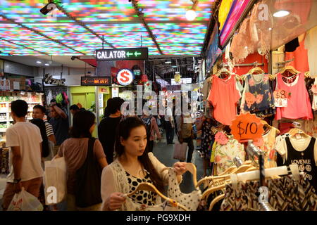 Una donna negozi per un abito nel mercato. Popolare sia tra i turisti e la gente del posto, Bugis Street Market è ben noto per essere uno dei posti più economici in Singapore per acquistare souvenir, accessori, abbigliamento, elettronica, lavori casalinghi e cosmetici. Foto Stock