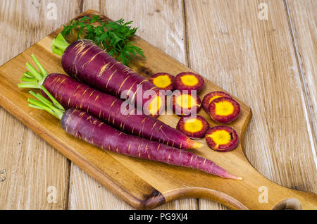 Tagliate a fette carota viola su sfondo di legno. Foto Studio Foto Stock