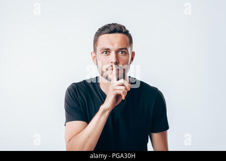 Giovane uomo tenendo il dito indice sulle labbra per chiedere silenzio. Concetto di segreto Foto Stock