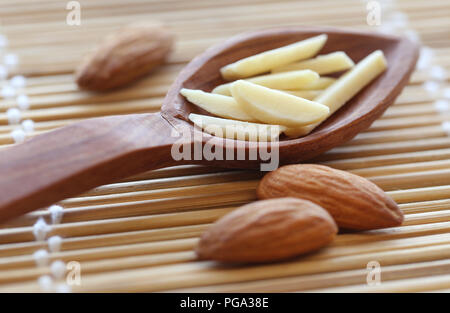 Organici di mandorle intere e tagliate a fette in un cucchiaio Foto Stock