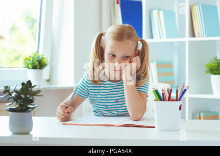 Ritratto di stanco little schoolgirl al tavolo in aula di luce Foto Stock