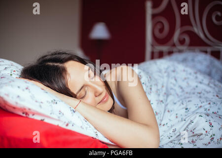 Giovane donna sorridente mentre dorme nel suo letto a casa. Concetto di relax Foto Stock