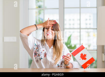 Giovane donna alla home azienda bandiera del Canada ha sottolineato con la mano sulla testa, sconvolto con vergogna e la sorpresa di fronte, arrabbiati e frustrati. Paura e sconvolti per Foto Stock